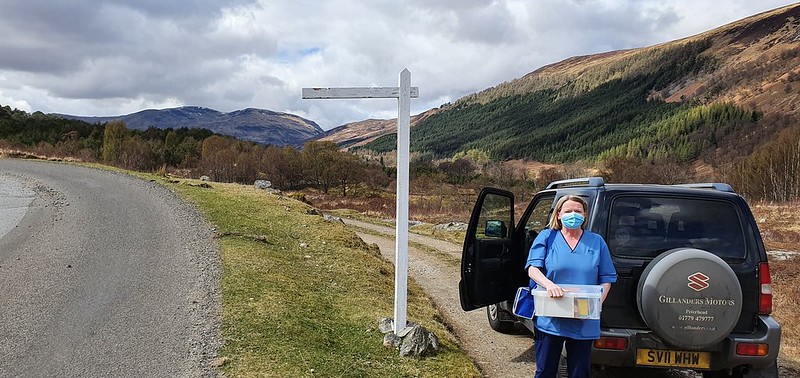 Nurse wearing face mask by car in front of hills