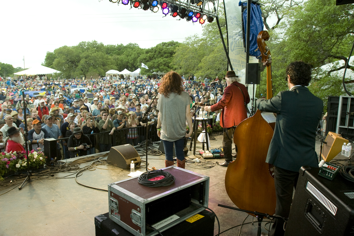 Guitarist, double bassist and singer on stage facing large audience