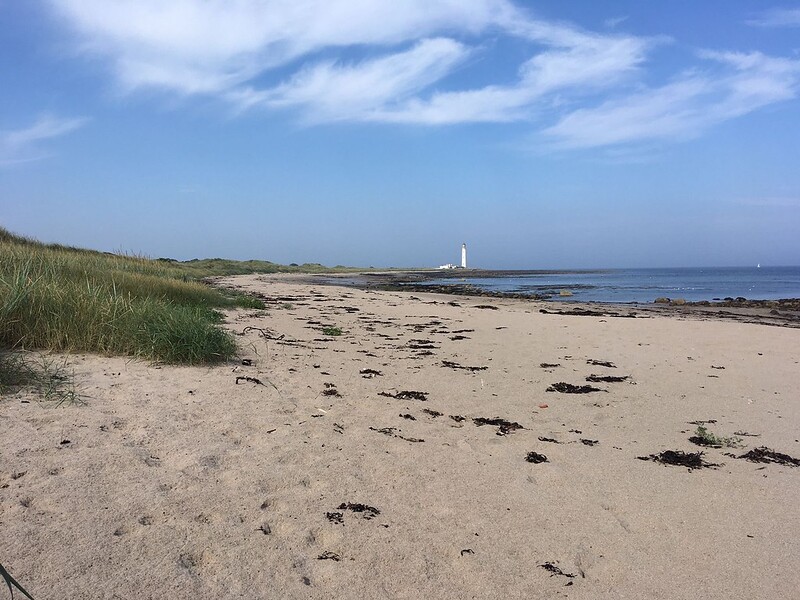Beach and shore line with white lighthouse
