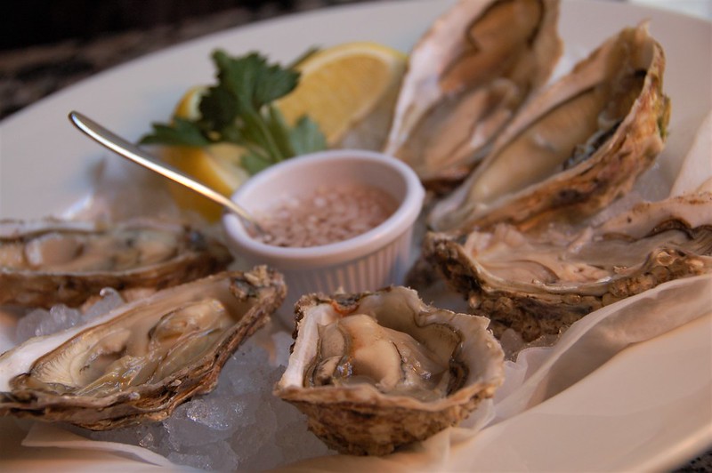 Plate of oysters on ice with lemon and dip