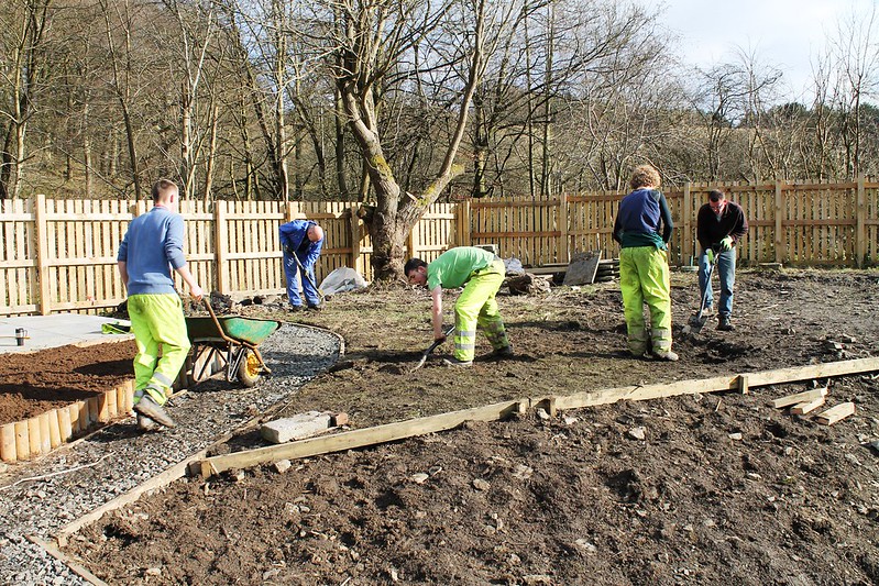 5 men digging ground and laying a path