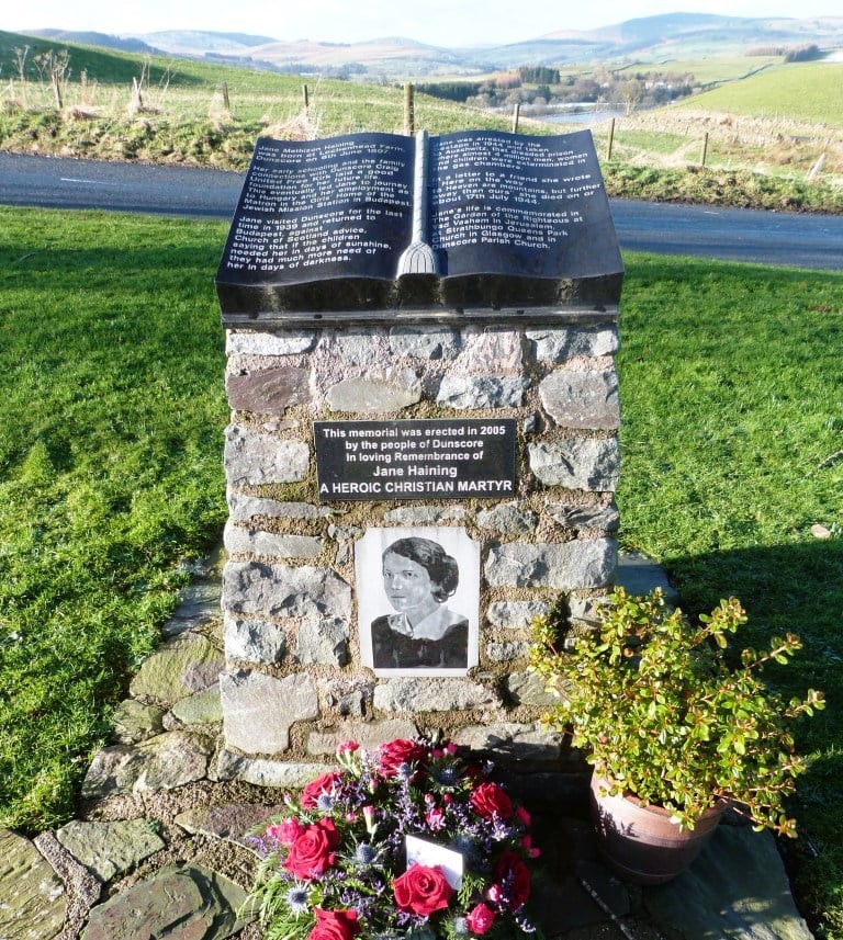 Memorial cairn with flowers set amongst grass and hills