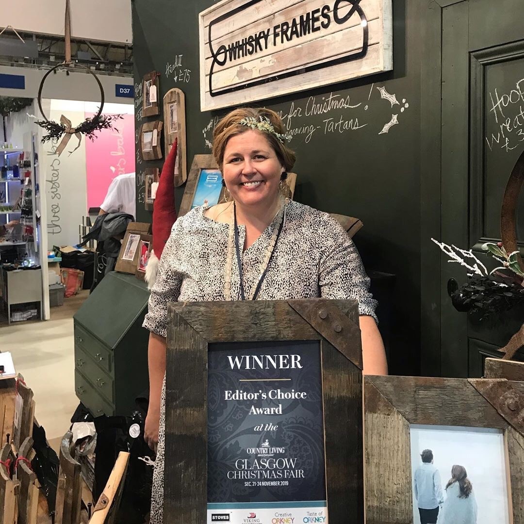 Woman in shop with framed award certificate