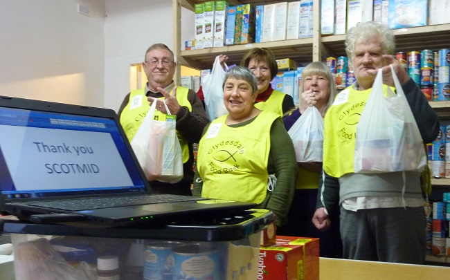 People at foodbank holding up shopping bags