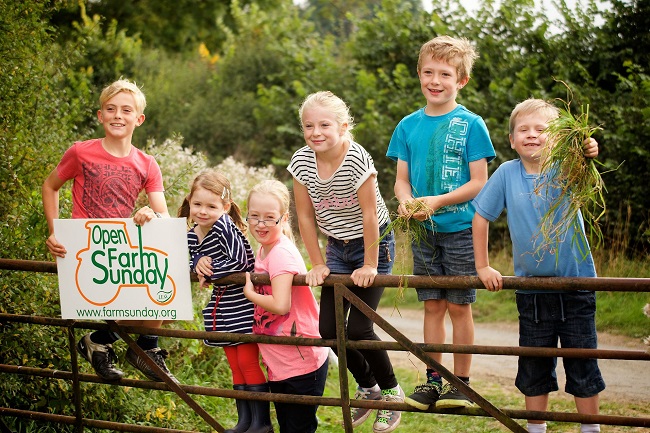 Children leaning on gate with Open Farm Sunday sign