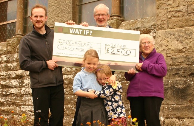 People holding a giant cheque outside a church