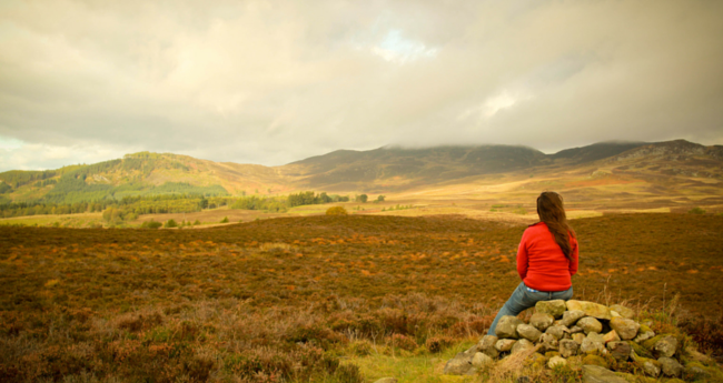 Person sitting on rocks in rural landscape
