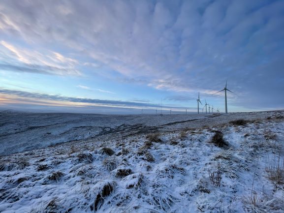 Winter view over snow covered moorland with wind turbines on the horizon