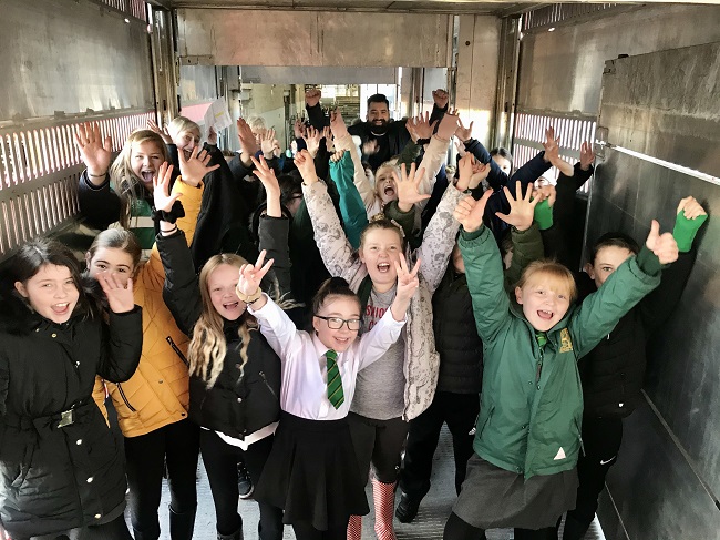 Children on farm visit with hands in air