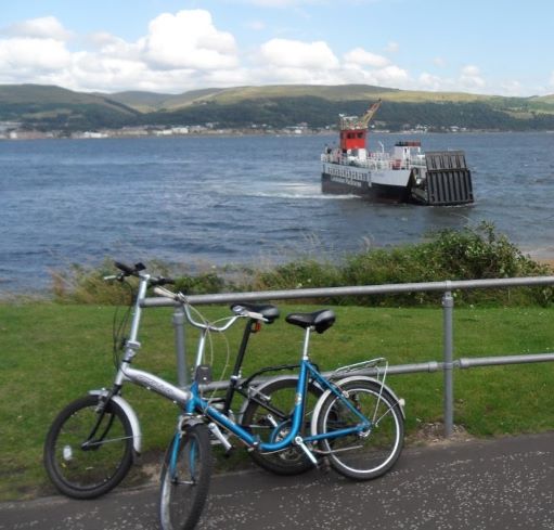 Two bikes parked with a view of a boat over the water to Cumbrae