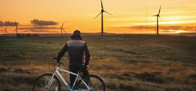 Cyclist i the foreground looking towards wind turbines  Credit: NetZeroScotland