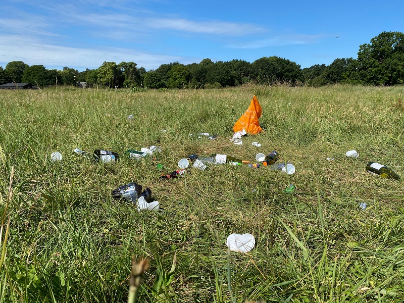 Bottles, plastic cups and plastic bag littering a grassy park