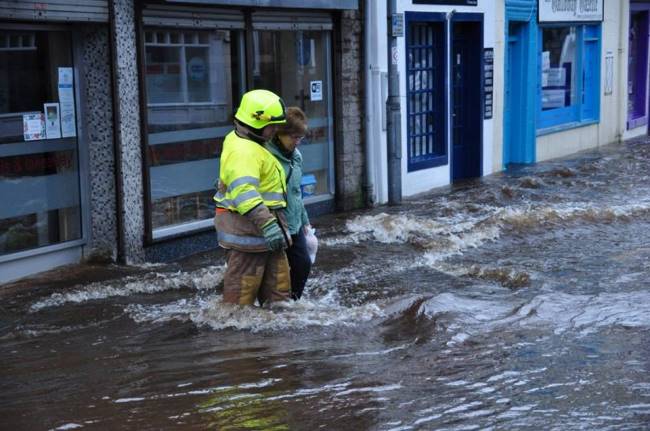Firefighter helps woman in flooded street