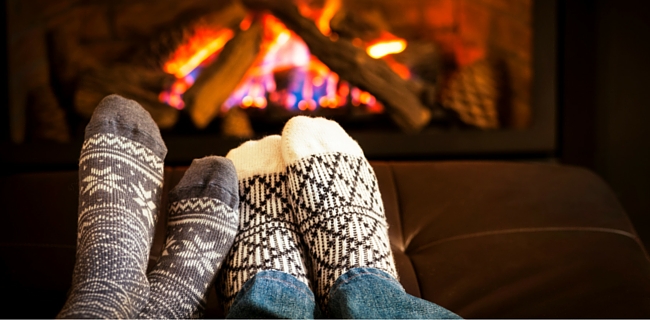 Two people warming their feet by a fire