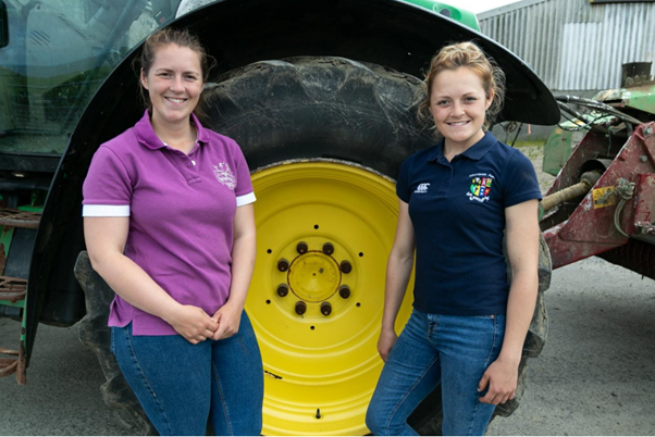 2 young farmers in front of huge tractor wheel