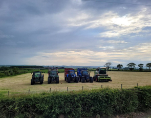 Five tractors lined up in a field