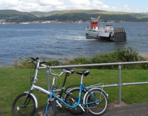 Two bikes leaning against railing with ferry in background