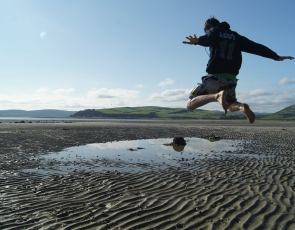 Boy jumping over seawater pool on beach 