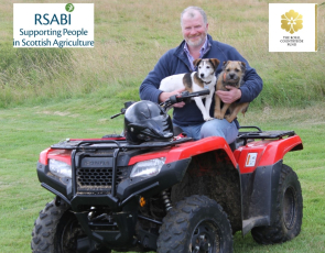 Farmer on stationery quad bike with two dogs