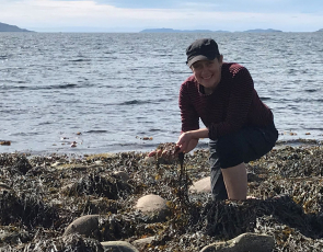 Woman kneeling on beach with seaweed