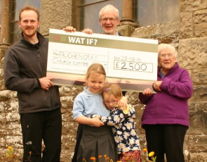 People holding a giant cheque outside a church
