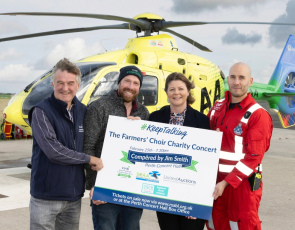 Four people in from of Air Ambulance promoting RSABI farmers choir concert