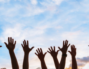 People with hands in the air against blue sky