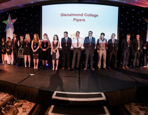 Group of 20 young people on stage behind compere