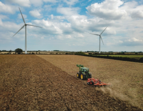 Tractor in field with wind turbines in the distance