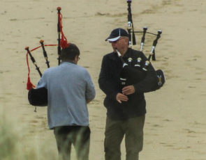 two men playing bagpipes on the beach