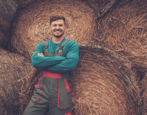 young farmer leaning against bales
