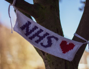 Knitted sign for NHS with a love heart tied on a tree