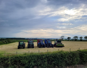 Four tractors and a chopper lined up in a freshly cut silage field