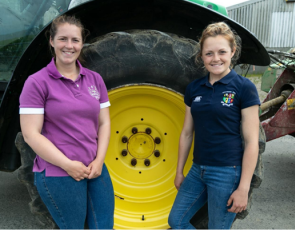 2 young farmers in front of huge tractor wheel