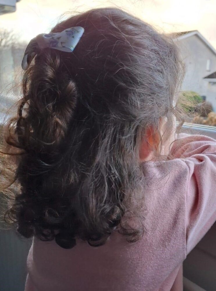 young child in pink top looking out of a window