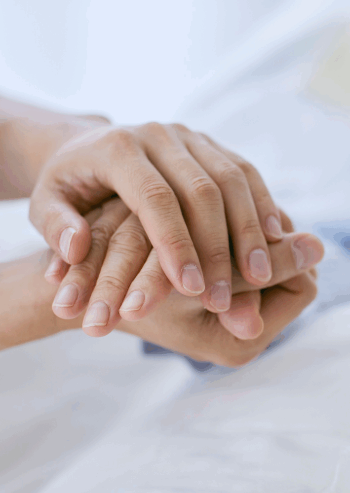 Close-up of a younger hand gently holding an older person's hand, symbolizing care and support.
