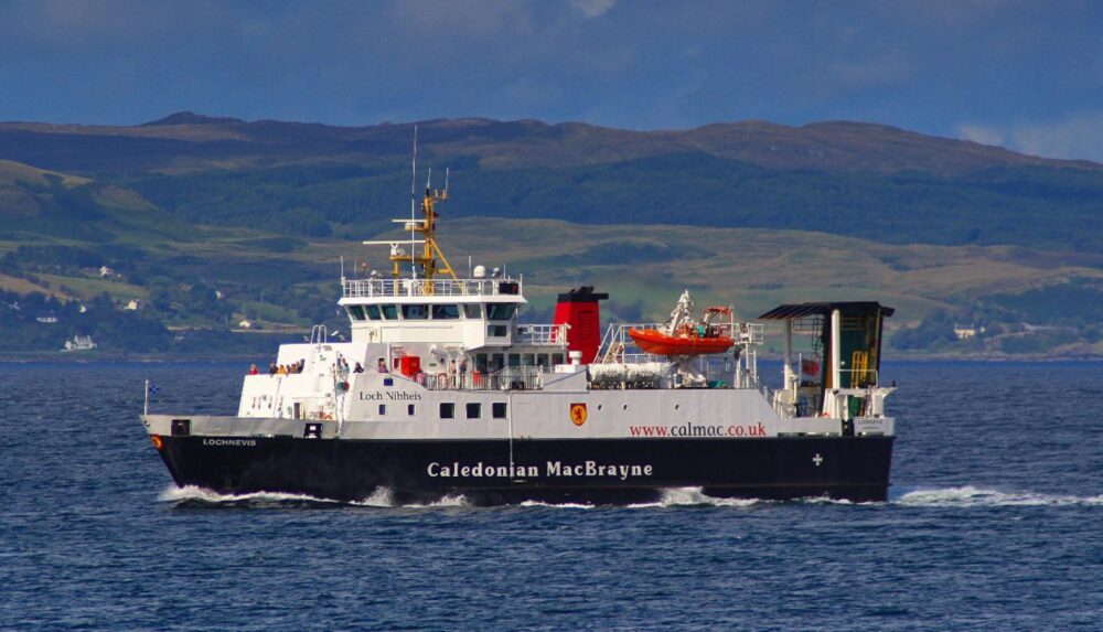 Caledonian MacBrayne ferry sailing on calm waters with hills in the background under a partly cloudy sky.
