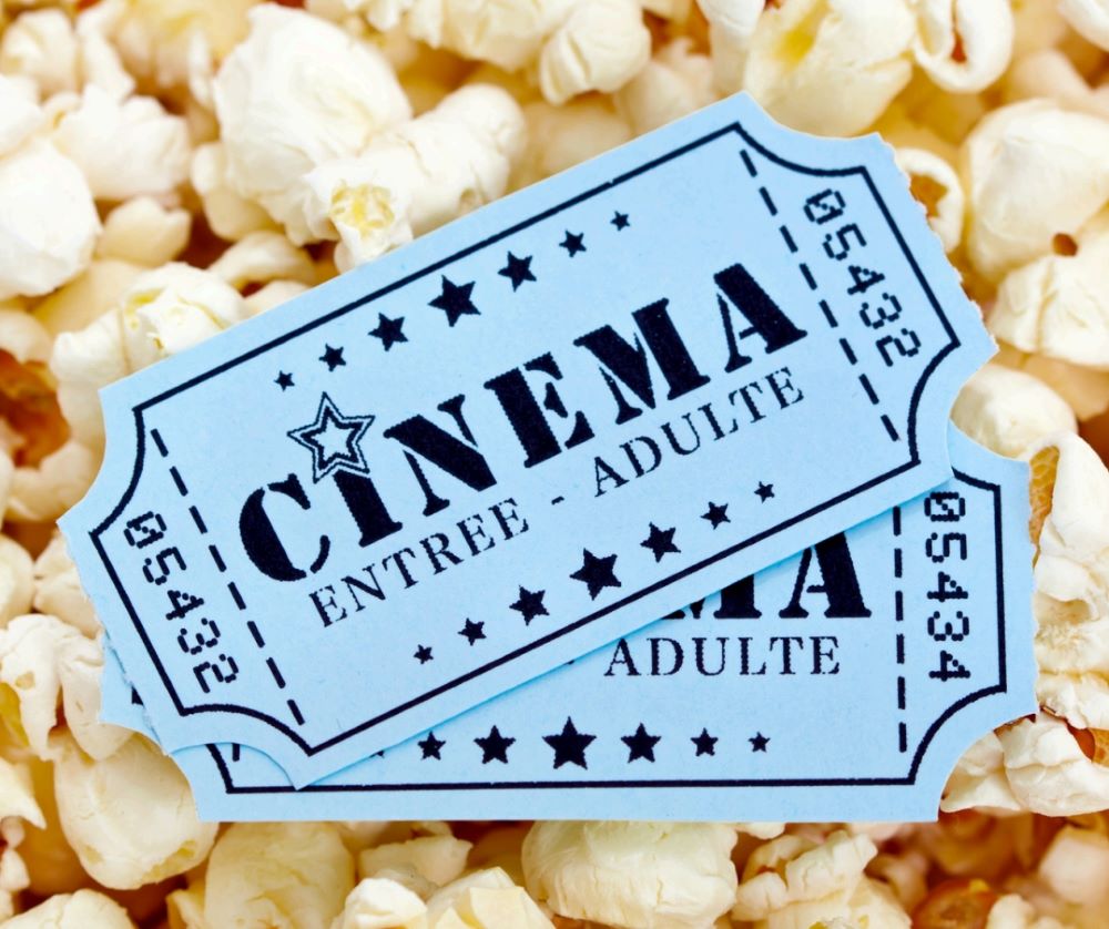 Close up picture of cinema tickets on top of popcorn