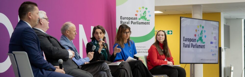 Panel discussion at the European Rural Parliament with five seated speakers engaged in conversation against a purple backdrop.