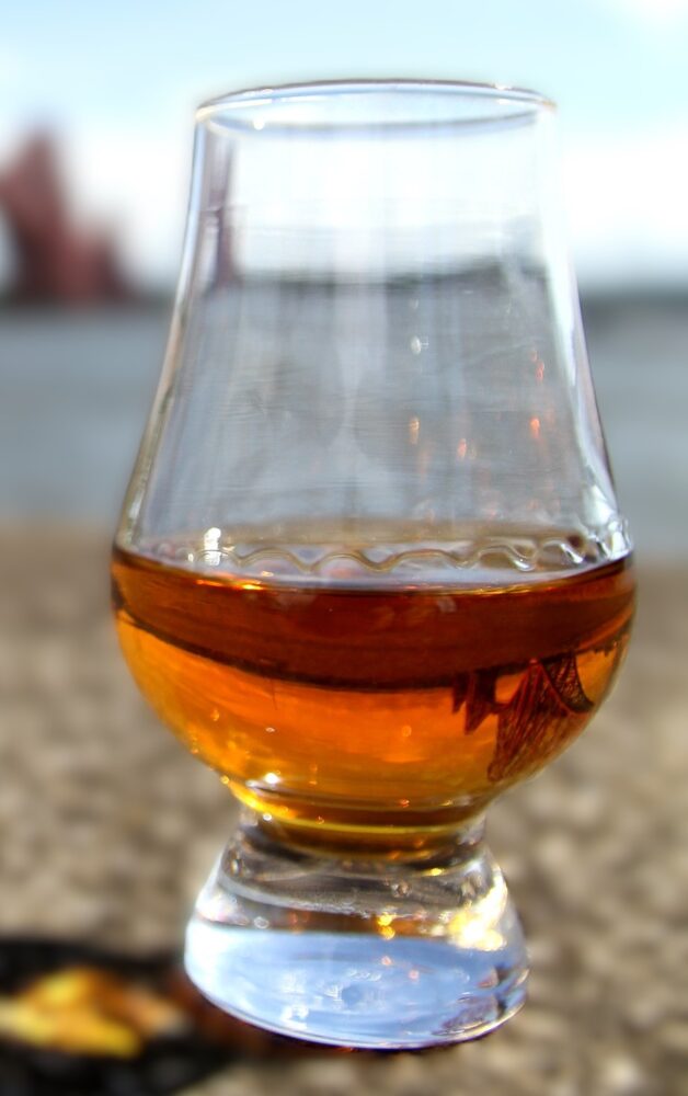 Glass of whisky on a shingle beach