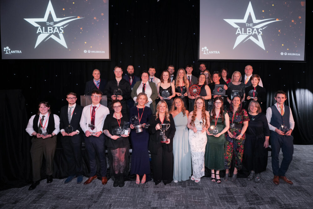Group of award winners posing on stage at The Albas event holding trophies and medals.