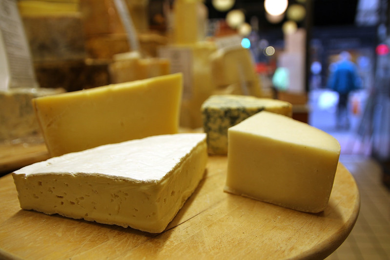 wedges of different cheeses on a wooden board