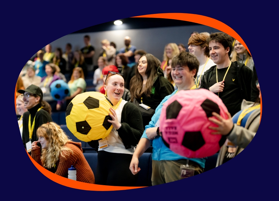 group of young people playing with oversized coloured footballs inside.