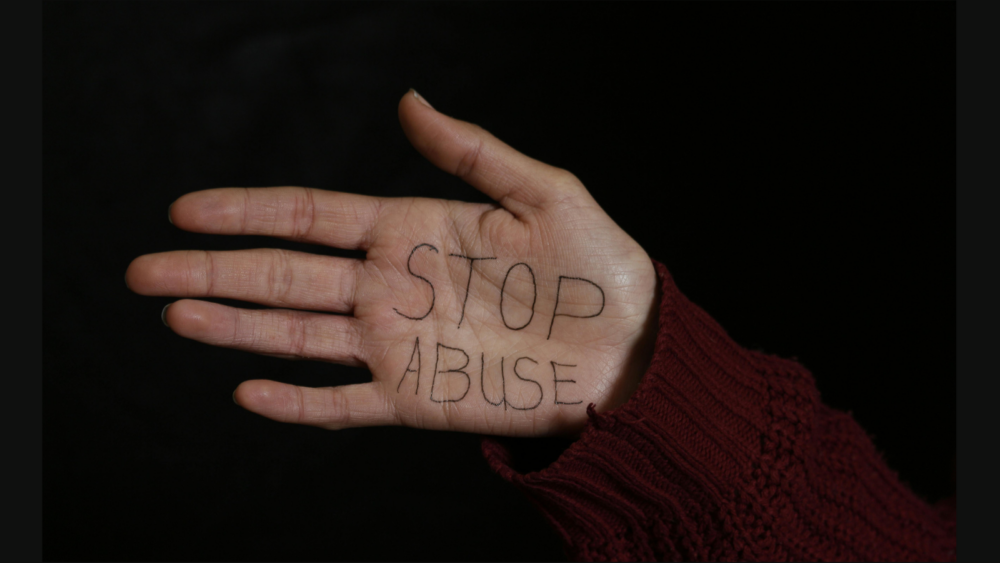 Woman Showing her Palm with Stop Abuse Text Written on it