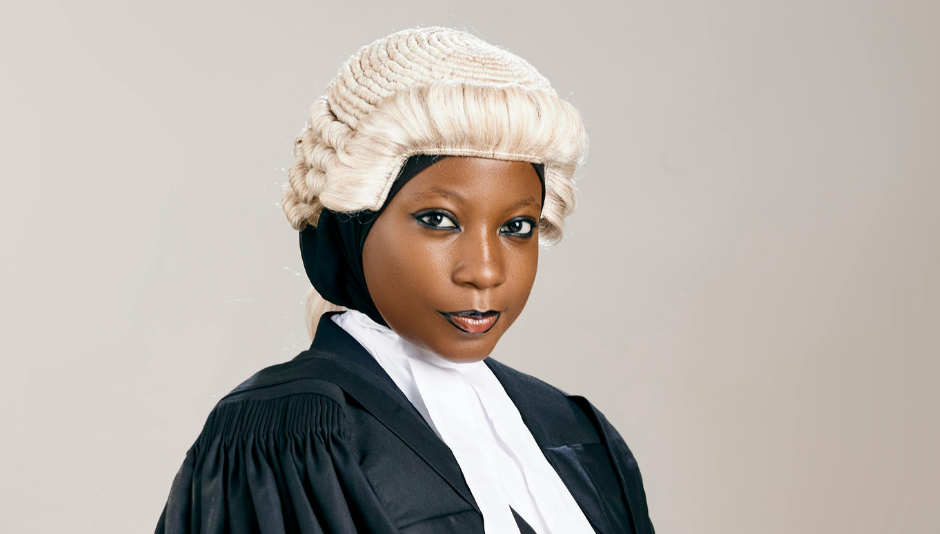 Woman in legal robes and wig against a light grey background