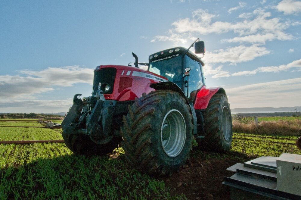 Modern red tractor in green field under a blue sky