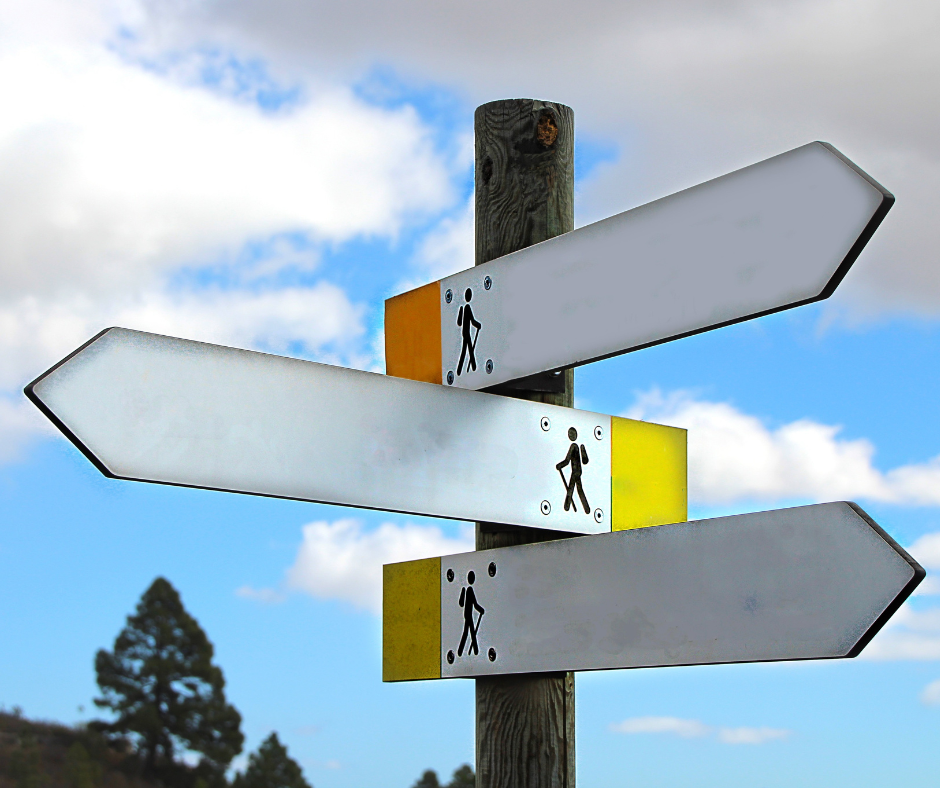 wooden pole with arrows pointing to colour coded paths