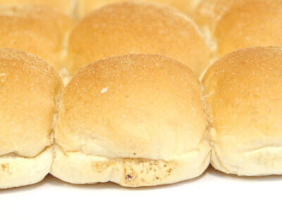 Freshly baked golden morning rolls arranged closely together on a white surface.