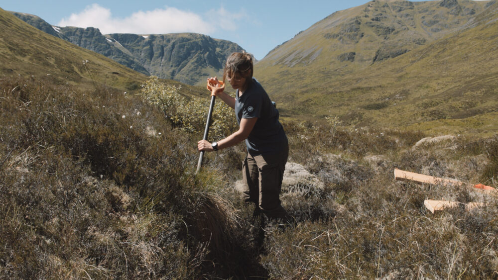 Outdoor scene of a person excavating soil in a remote, mountainous region.